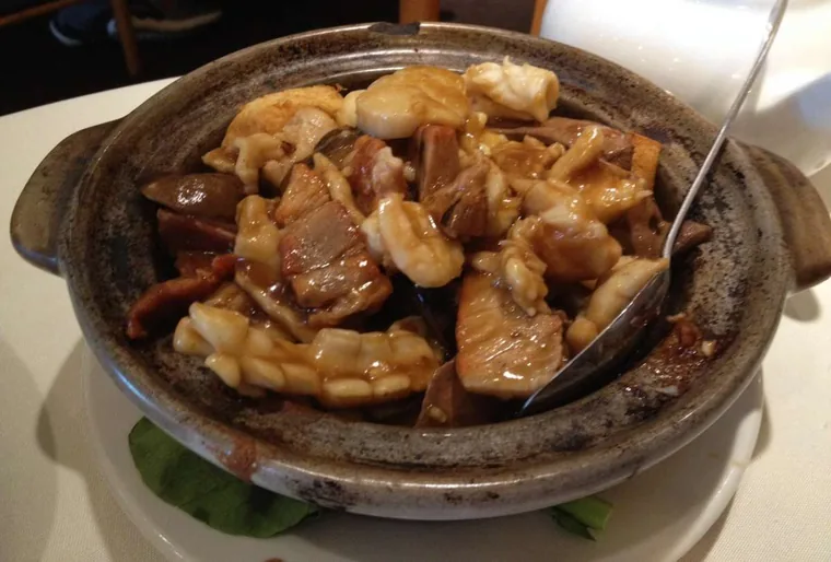 Clay pot filled with braised pork, squid, mushrooms and tofu in a glossy brown sauce